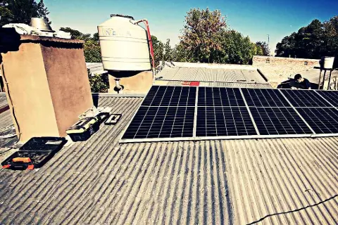 Instalación de paneles fotovoltaicos sobre un techo de chapa, con herramientas y tanque de agua al lado