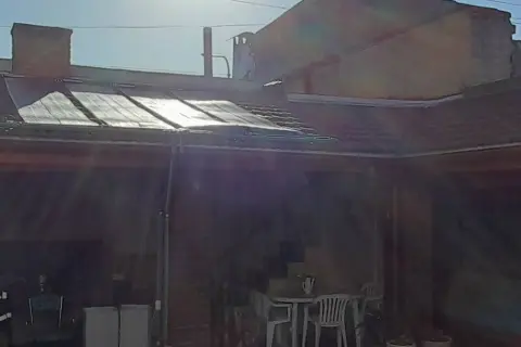 Colectores solares sobre el techo de una galería, con mesa y sillas debajo