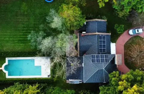 Vista aérea de una casa con paneles sobre el techo y pileta