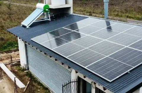 Paneles solares y termotanque solar sobre el techo de un galpón rural