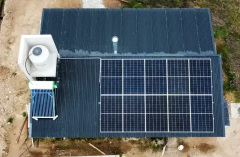 Vista aérea de paneles solares y un termotanque solar sobre un techo de chapa