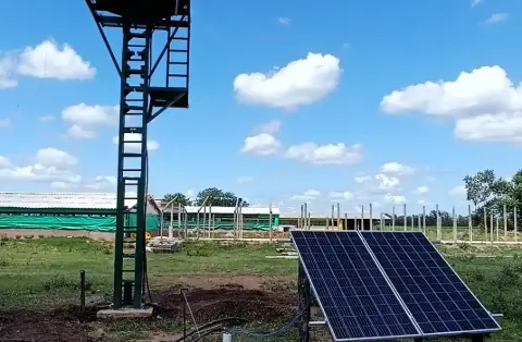 Paneles solares sobre una estructura en el campo, junto a una torre