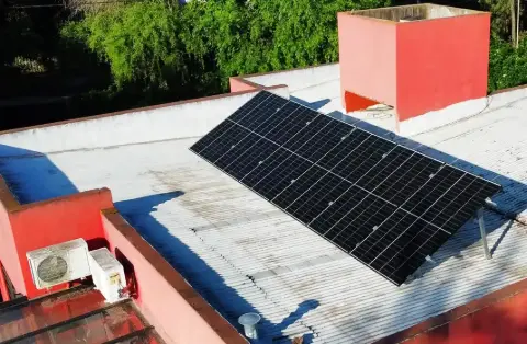 Paneles solares inclinados sobre una terraza, junto a un equipo de aire acondicionado