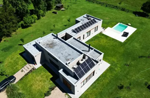 Vista aérea de una casa moderna con paneles en el techo y pileta