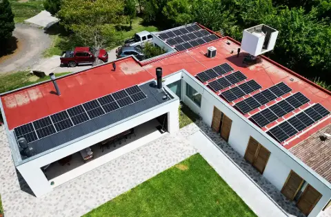 Vista aérea de paneles solares sobre el techo rojo de una casa de campo