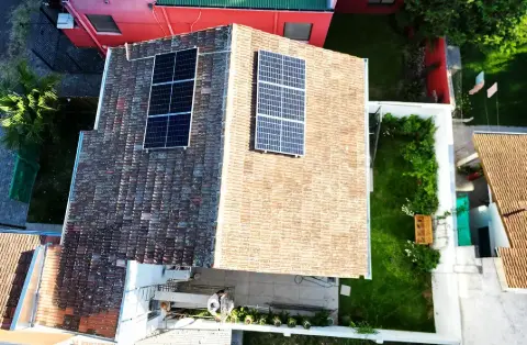 Dos grupos de paneles solares sobre un techo de tejas, vista aérea