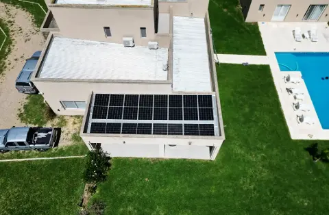 Paneles solares sobre el techo de una casa con pileta, vista aérea