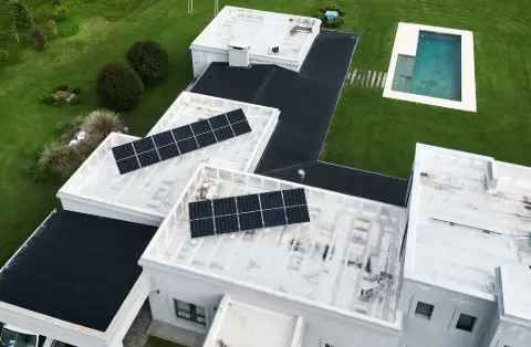 Paneles solares sobre techos planos de una casa moderna con pileta, vista aérea