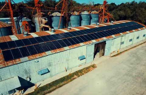 Paneles solares sobre el techo de un galpón junto a silos